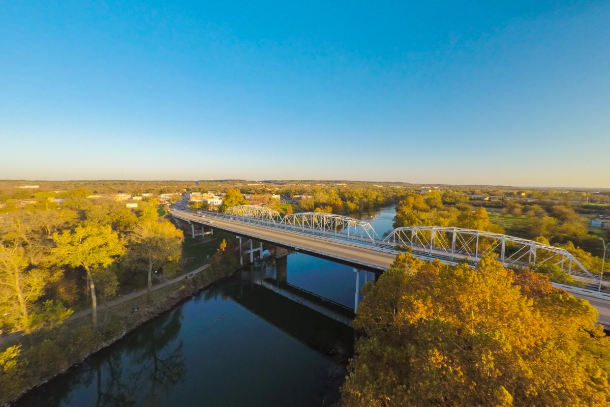 Colorado River and steel bridge surrounded by fall foliage in Bastrop